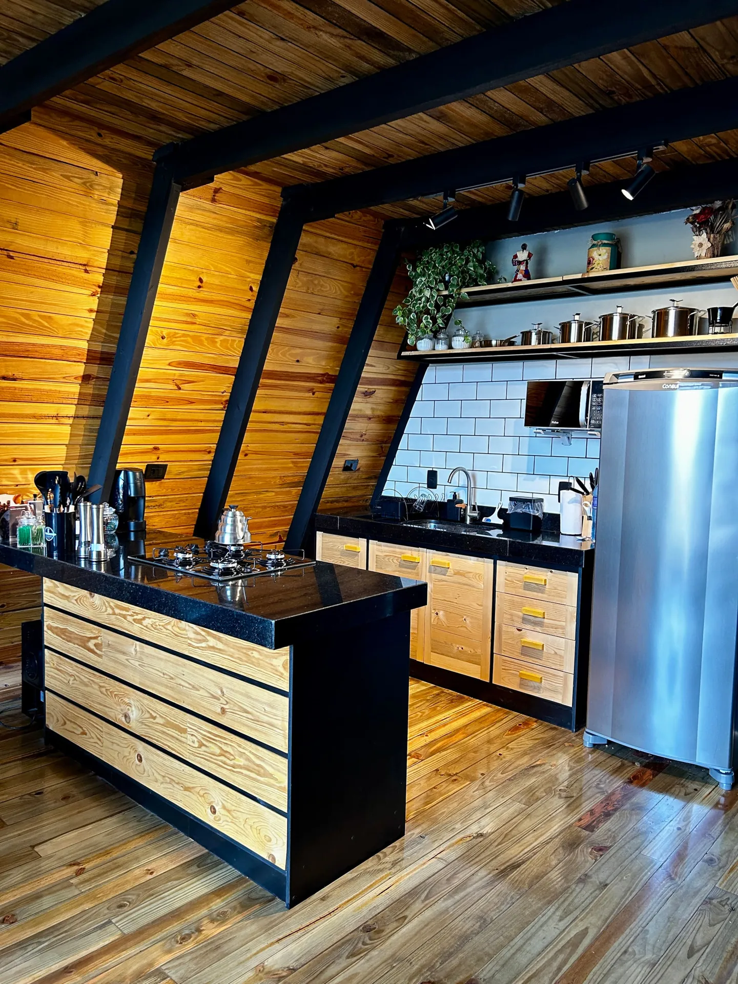 Cozinha completa com bancada, geladeira inox e prateleiras de madeira