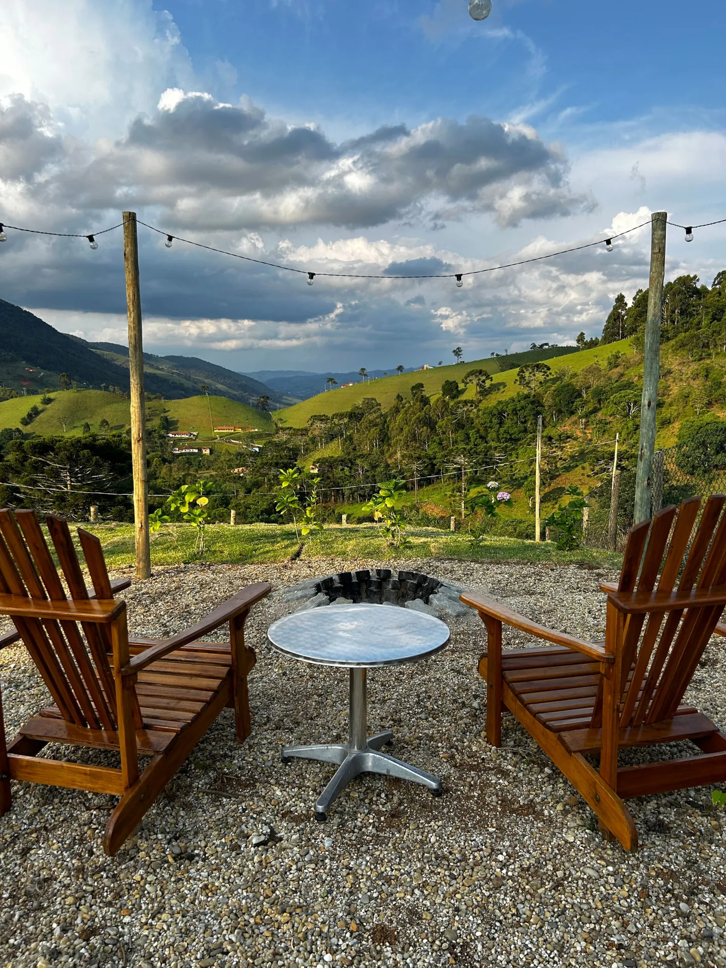 Cadeiras de madeira em volta do fogo de chão, com o vale e as montanhas